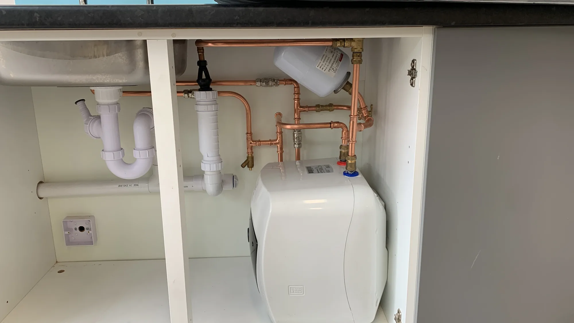 Tidy heating pipework installed under a unit in Lancashire